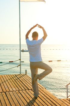 man standing on a pier on one leg and holds the balance