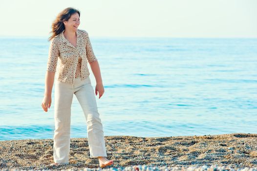 cheerful woman walking along the beach barefoot