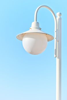 solitary white street light against the blue sky