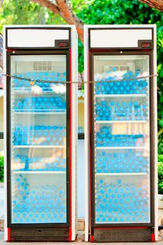 two refrigerators full of water bottles under lock and key