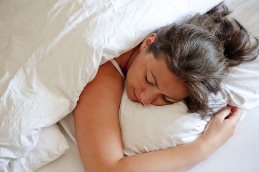 girl sleeping on his stomach hugging pillow