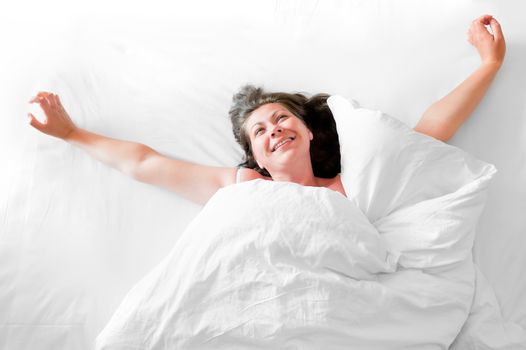 Photo of a young woman waking up happy with a morning stretch