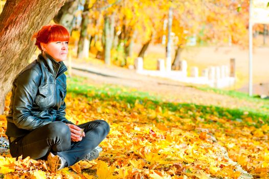 girl with red hair in the park resting in a maple