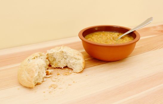 Soup served with a crusty bread roll torn in two with copy space