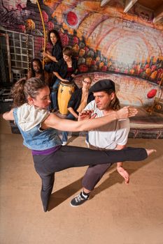 Capoeira instructor teaching woman how to do a roundhouse kick