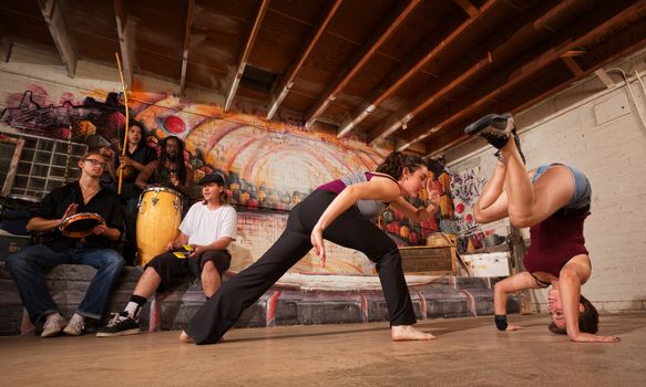 Group of capoeira performers with music in urban building