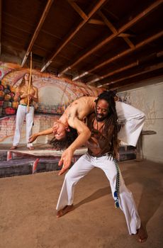 Capoeira performer holding partner in back bending over shoulders