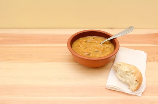 Serving of chunky vegetable soup, half a bread roll and a napkin - with copy space