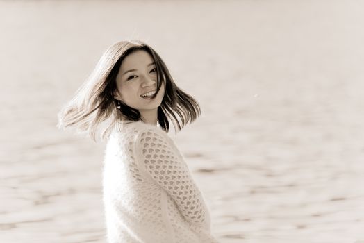 Portrait of young attractive woman sitting on a rock next to a river looking back with floating hair