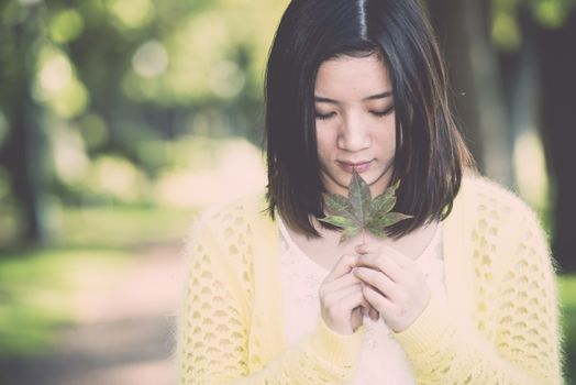 Portrait of young attractive woman holding a leaf close to mouth at an end of a road