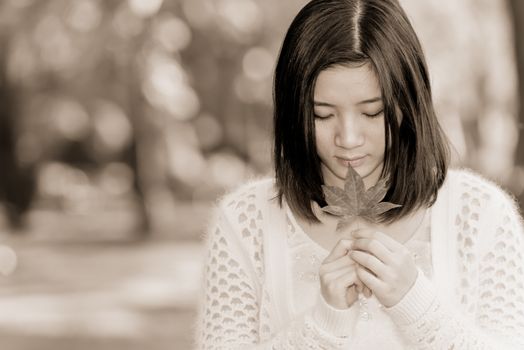 Portrait of young attractive woman holding a leaf close to mouth at an end of a road