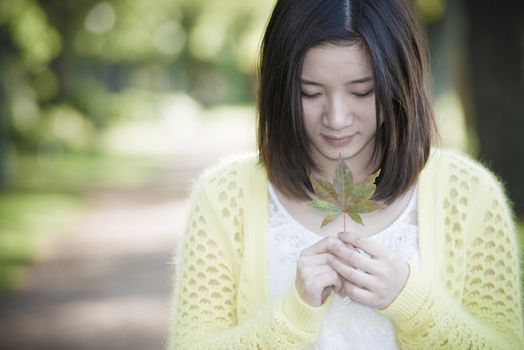 Portrait of young attractive woman holding a leaf close to mouth at an end of a road