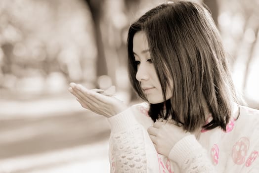 Cute young girl holding a handful of leafs at the end of a park road