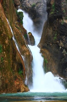 water falling to river between huge rocks 