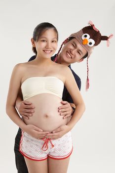 Smiling husband hugging her pregnant wife