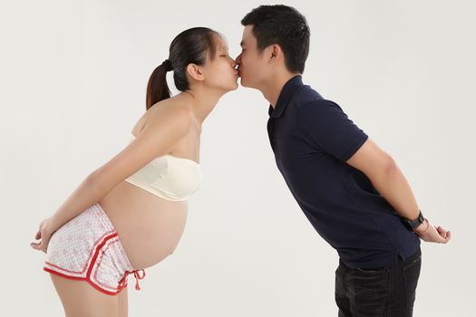 A young husband is kissing his pregnant wife