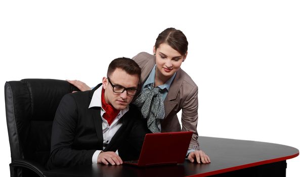 Young casual couple looking to a red notebook on a black desk, isolated against a white background.