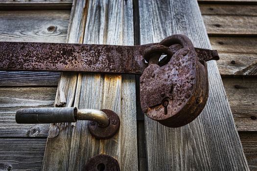 Old latch with padlock on gatees