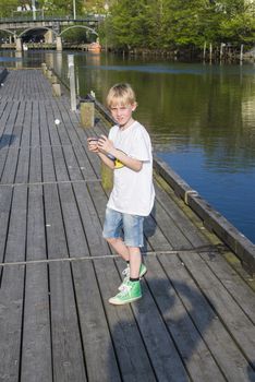 The boy strolling along the Tista River in Halden, Norway with grandpa and check if there is any mail on iPhone