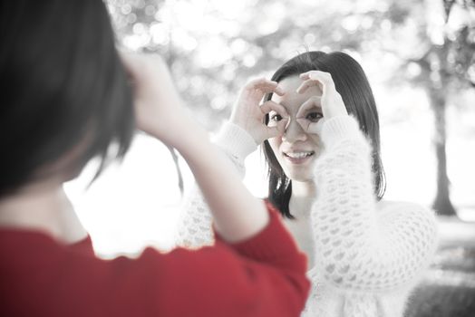 Two young girls posing hand signals to each other in a park showing friendship