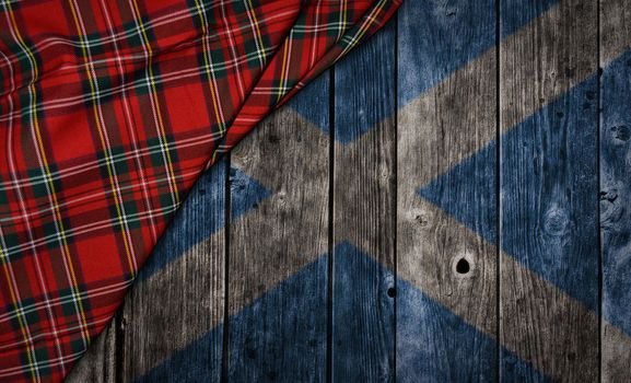 tartan textile on wooden background with scotland flag