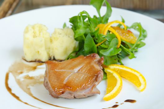 close up roasted duck breast  served with mashed potatoes and orange , fresh salad and white wine sauce