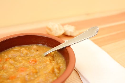 Closeup of chunky vegetable soup with pieces of bread roll