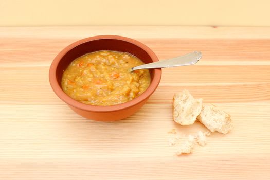 Vegetable soup on wooden table with remainder of bread roll