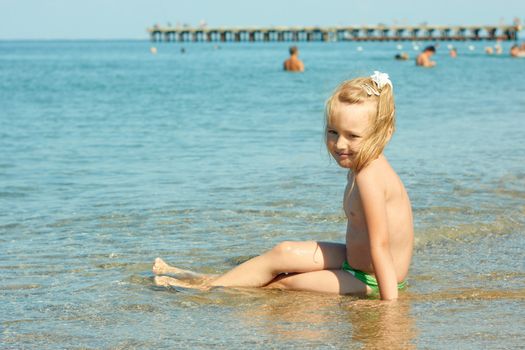 Little girl on the turquoise sea water surface in shallow coastal area near the pear