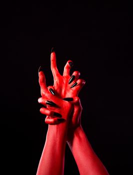 Red demonic hands with black nails, Halloween theme, isolated on black background  