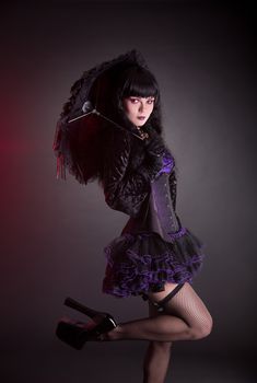 Portrait of gothic Lolita girl with umbrella, studio shot on black background 