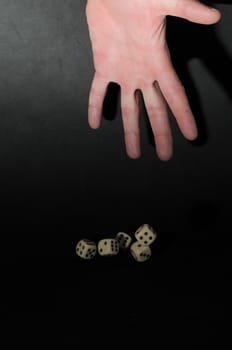 One Left Male Hand Playing Dice on a Black Background