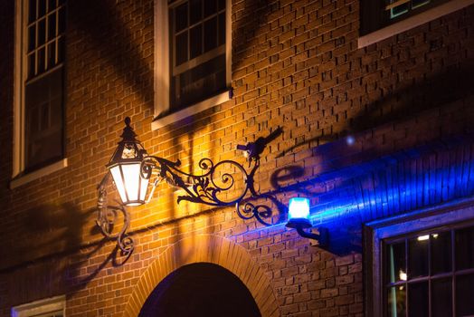 Alleyway by night with blue security light on brick wall