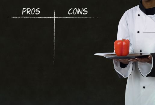 African American chef holding healthy food with chalk pros and cons on blackboard background