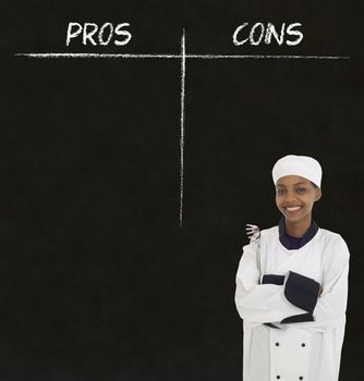 African American woman chef holding utensil with chalk pros and cons on blackboard background