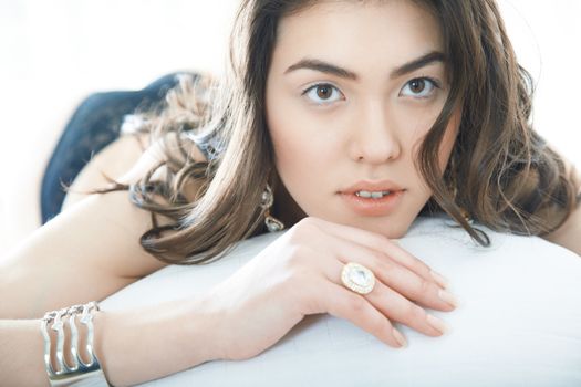 Brunette lady with jewelry laying on the bed