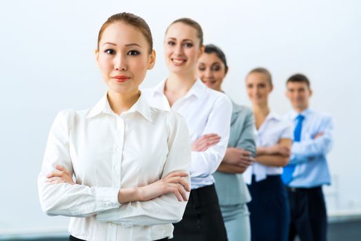 group of business people standing in a row, smiling and crossing his arms