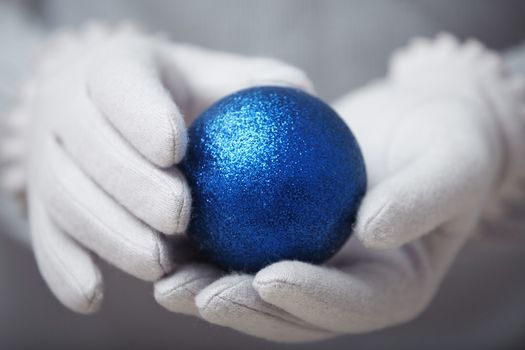 Human hands in warm mittens holding Christmas ball