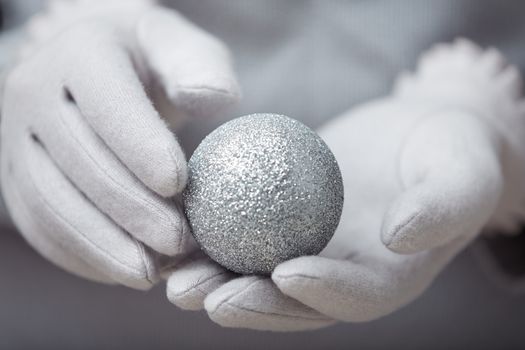 Human hands in warm mittens holding Christmas ball