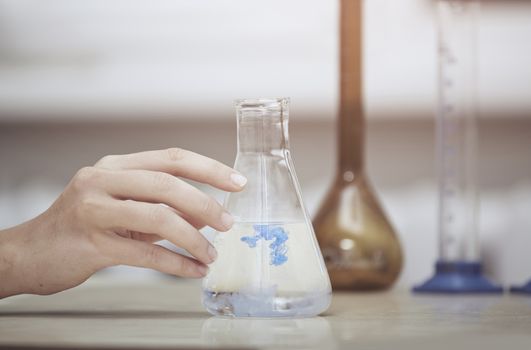 Hand of laboratory technician holding flask with chemical