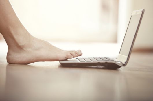 Human foot on a small laptop. Close-up view