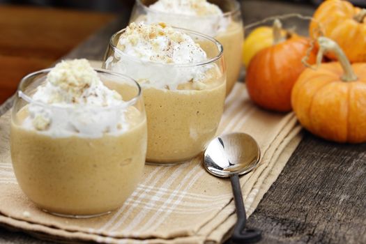 Three fresh Pumpkin Smoothies against a rustic background with shallow depth of field. Selective focus on center smoothie. 