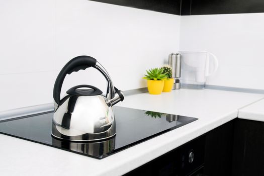 Steel kettle in modern kitchen with induction stove 