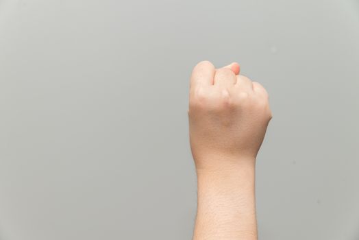 Human hand with closed fist on gray background