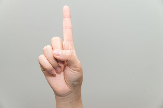 Human hand with one finger sticking up on light gray background