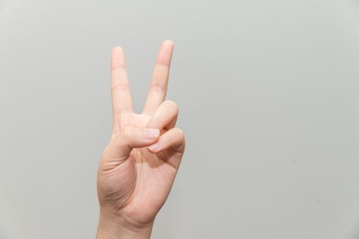 Human hand with two finger posing on light gray background