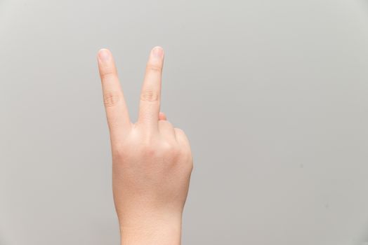 Human hand with two finger posing on light gray background