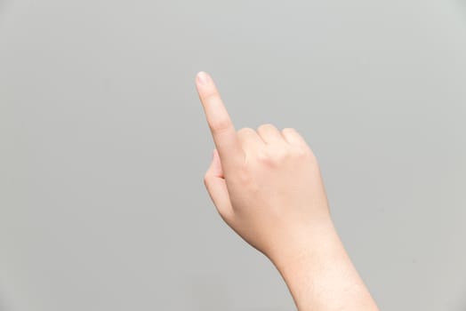 Human hand with one finger touching imaginary tablet on gray background