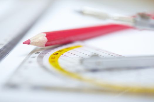 Red pencil with compasses and rulers on a paper. Extremely close-up photo