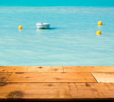 Wooden decking or picnic table on St Martin in Caribbean in idyllic dreamlike location with a powerboat moored just off the harbor in the turquoise ocean